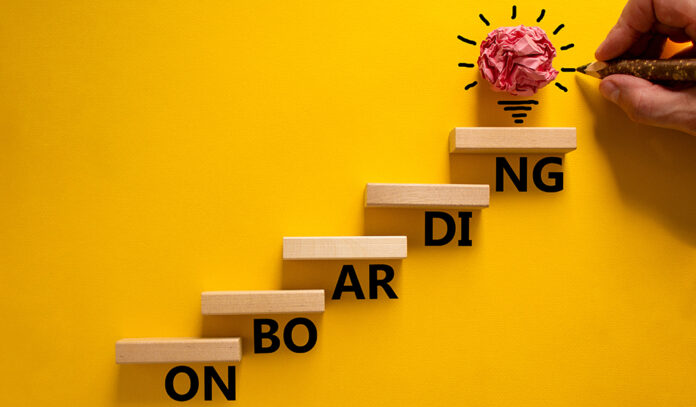 Success onboarding process symbol. Wood blocks stacking as step stair on yellow background, copy space. Businessman hand and light bulb. Word 'onboarding'. Business and onboarding concept.